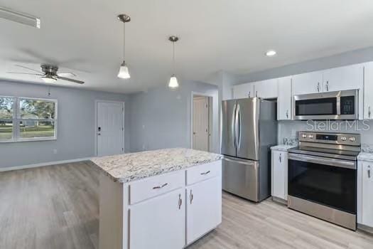 kitchen with stainless steel appliances, a kitchen island, ceiling fan, decorative light fixtures, and white cabinetry