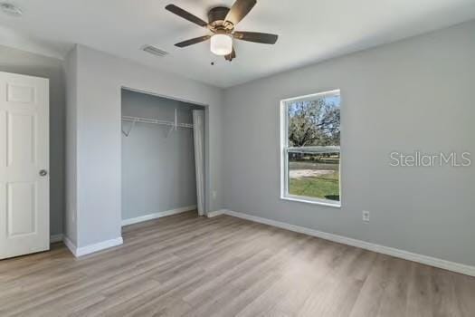 unfurnished bedroom with multiple windows, ceiling fan, a closet, and light hardwood / wood-style floors