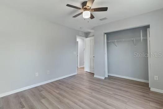 unfurnished bedroom with a closet, light hardwood / wood-style flooring, and ceiling fan