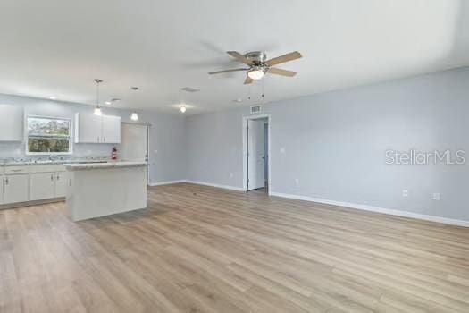 kitchen featuring pendant lighting, a center island, ceiling fan, light hardwood / wood-style floors, and white cabinetry