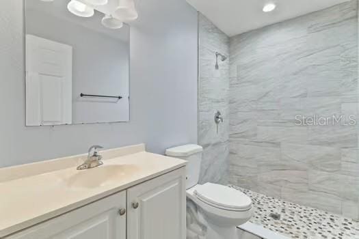 bathroom featuring vanity, toilet, and tiled shower