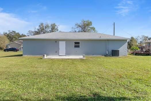 rear view of property with a yard, central AC unit, and a patio area