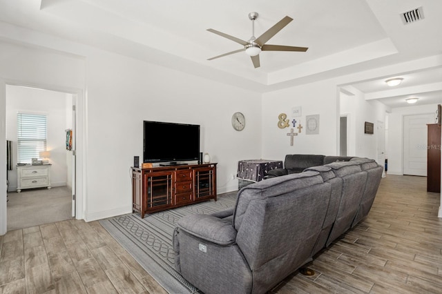 living room with ceiling fan and a raised ceiling