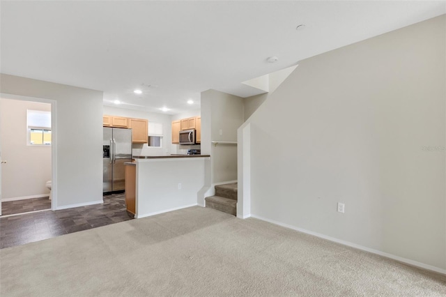 kitchen with stainless steel appliances, light brown cabinetry, dark carpet, and kitchen peninsula