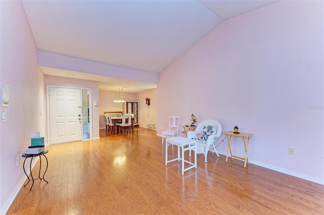 living area featuring a chandelier, hardwood / wood-style flooring, and vaulted ceiling