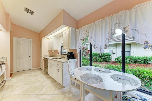 kitchen with light stone counters, stainless steel dishwasher, sink, white cabinetry, and lofted ceiling