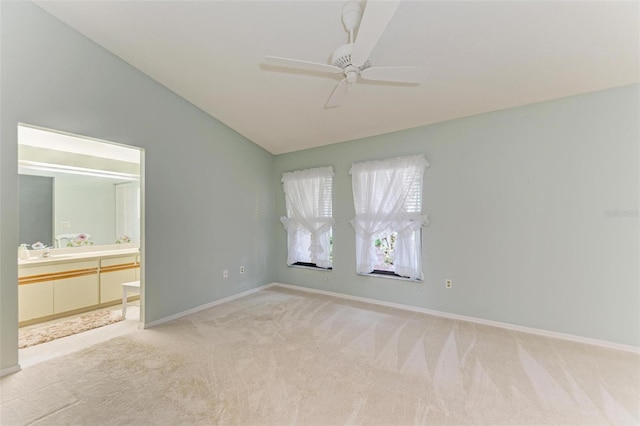 unfurnished bedroom featuring ceiling fan, ensuite bathroom, light carpet, and vaulted ceiling