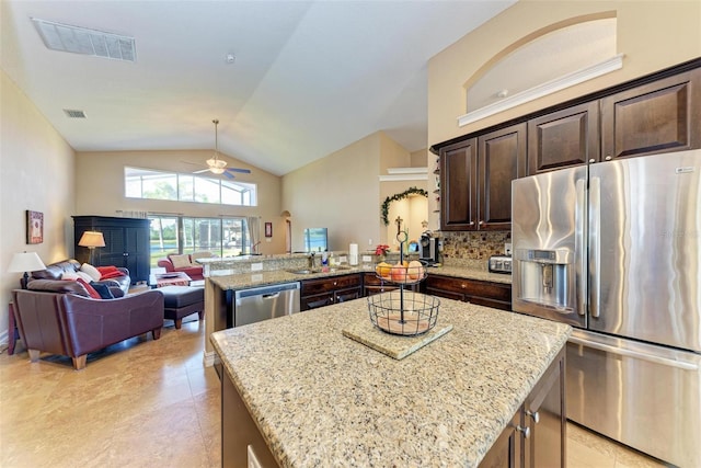 kitchen with appliances with stainless steel finishes, kitchen peninsula, light stone countertops, and a kitchen island