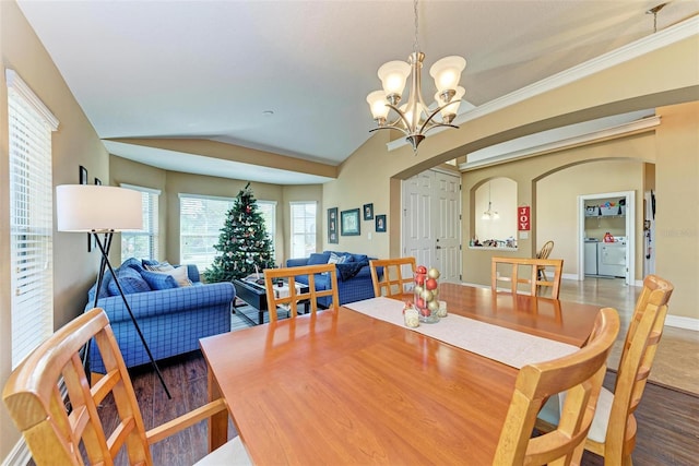 dining space with lofted ceiling, an inviting chandelier, separate washer and dryer, and dark wood-type flooring