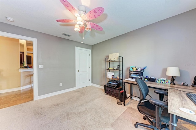 carpeted home office featuring ceiling fan