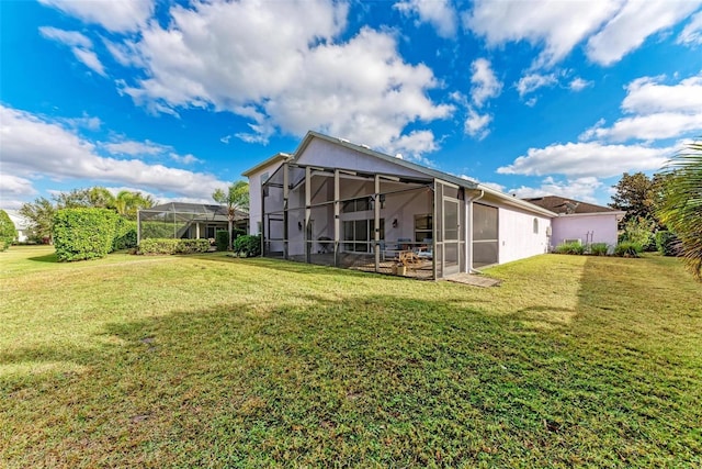 rear view of house with glass enclosure and a yard