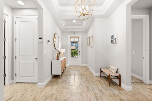 entryway featuring ornamental molding, a tray ceiling, and a notable chandelier