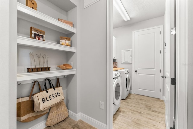 washroom featuring cabinets, independent washer and dryer, a textured ceiling, and light hardwood / wood-style flooring