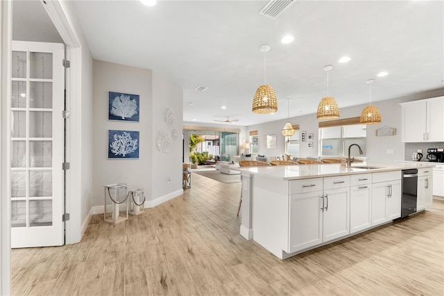 kitchen with hanging light fixtures, white cabinetry, sink, and a kitchen island with sink