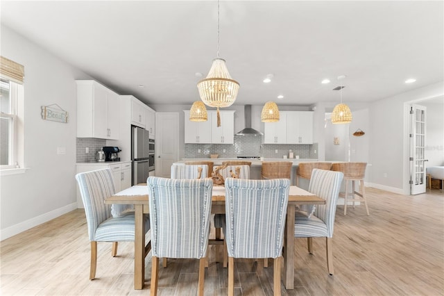 dining space with light wood-type flooring and a notable chandelier