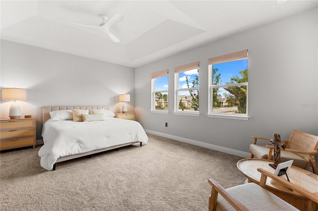 bedroom featuring a raised ceiling, ceiling fan, and carpet