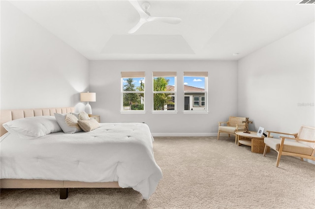 bedroom with carpet flooring, a tray ceiling, and ceiling fan