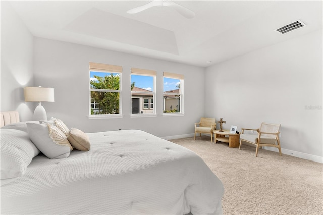 bedroom with a tray ceiling, ceiling fan, and carpet flooring