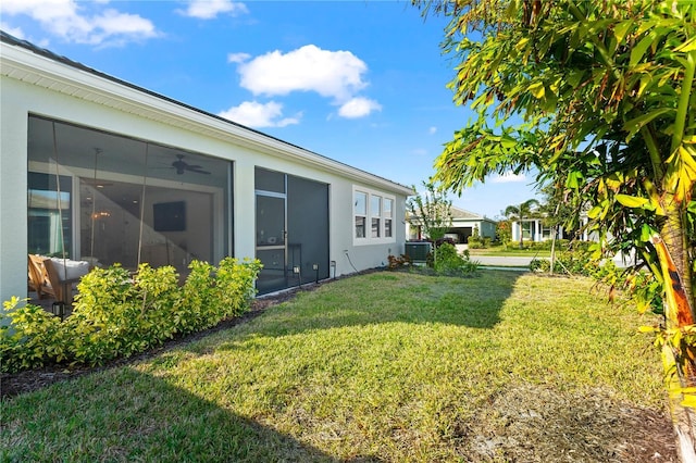 view of yard with ceiling fan, central AC unit, and a sunroom