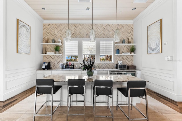 kitchen with white cabinets, pendant lighting, light stone counters, and a breakfast bar area