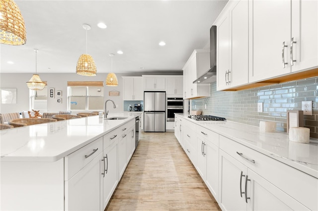 kitchen featuring appliances with stainless steel finishes, backsplash, a spacious island, wall chimney range hood, and white cabinets