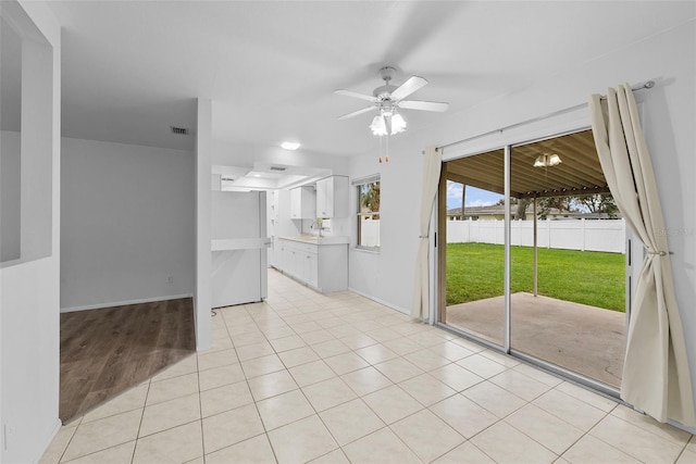 kitchen with white fridge, white cabinets, ceiling fan, and light tile patterned floors