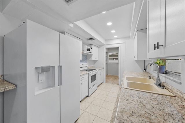 kitchen featuring white appliances, white cabinets, sink, and light tile patterned floors