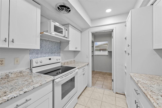 kitchen with white appliances, white cabinets, light tile patterned floors, and light stone counters