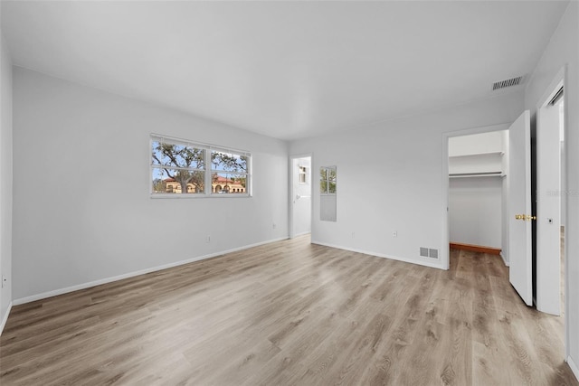 unfurnished bedroom with a spacious closet, a closet, and light wood-type flooring