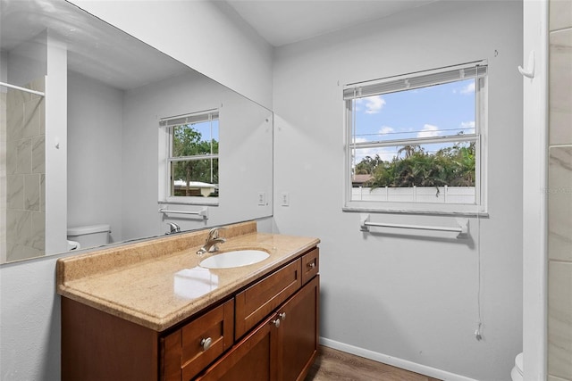 bathroom featuring toilet, vanity, hardwood / wood-style floors, and plenty of natural light