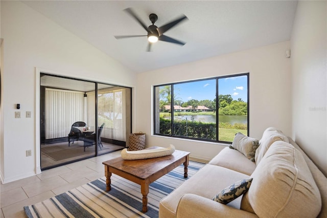 tiled living room featuring ceiling fan, a healthy amount of sunlight, a water view, and lofted ceiling