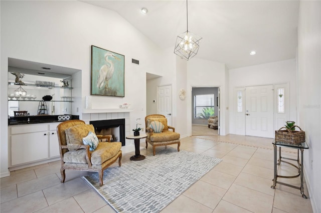 foyer entrance featuring an inviting chandelier, high vaulted ceiling, a fireplace, and light tile patterned floors