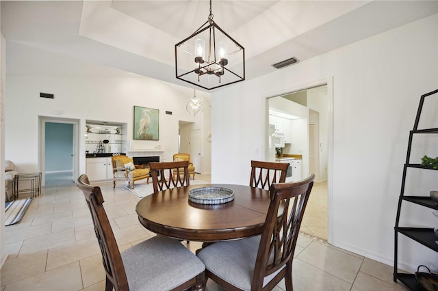 dining room with light tile patterned flooring, a raised ceiling, and a notable chandelier