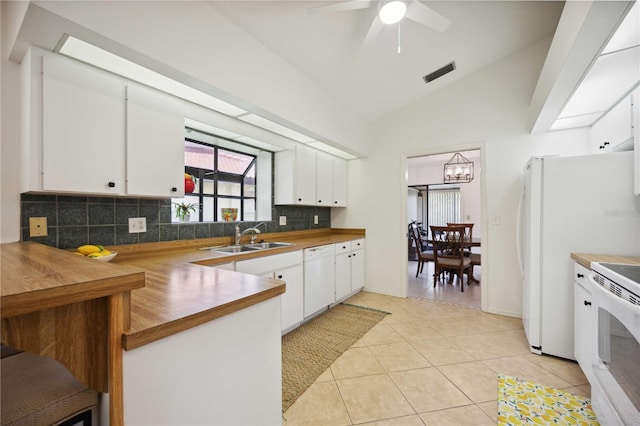 kitchen featuring white cabinets, vaulted ceiling, sink, and light tile patterned floors