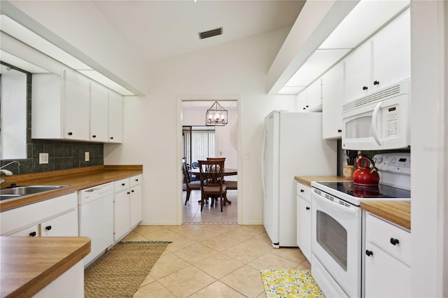 kitchen featuring white appliances, white cabinets, light tile patterned floors, and sink