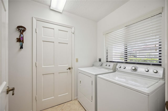 washroom featuring a textured ceiling, light tile patterned floors, and washer and clothes dryer