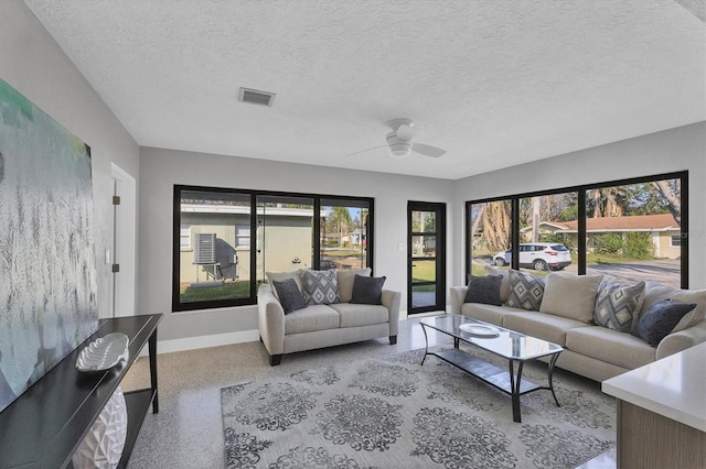 living room featuring ceiling fan and a textured ceiling