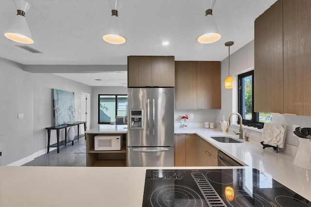 kitchen featuring kitchen peninsula, decorative light fixtures, stainless steel fridge with ice dispenser, black electric stovetop, and sink