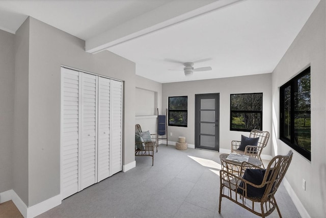 living area with ceiling fan and beam ceiling