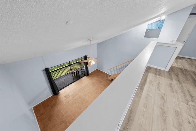 stairs with hardwood / wood-style flooring, ceiling fan, lofted ceiling, and a textured ceiling