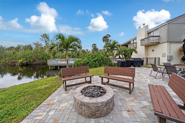 view of patio featuring a water view, a fire pit, and a balcony