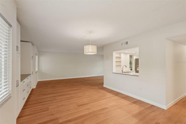 2753 Orchid Oaks Dr Unit 104, Sarasota, FL 34239 - unfurnished dining area with light wood-style flooring, baseboards, plenty of natural light, and a sink