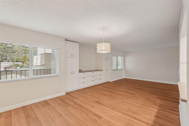 2753 Orchid Oaks Dr Unit 104, Sarasota, FL 34239 - empty room featuring light wood-style flooring, baseboards, and a textured ceiling