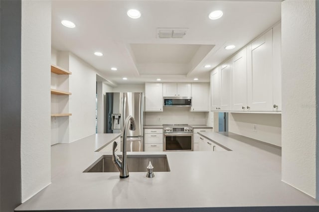 2753 Orchid Oaks Dr Unit 104, Sarasota, FL 34239 - kitchen featuring appliances with stainless steel finishes, recessed lighting, a sink, a raised ceiling, and white cabinetry