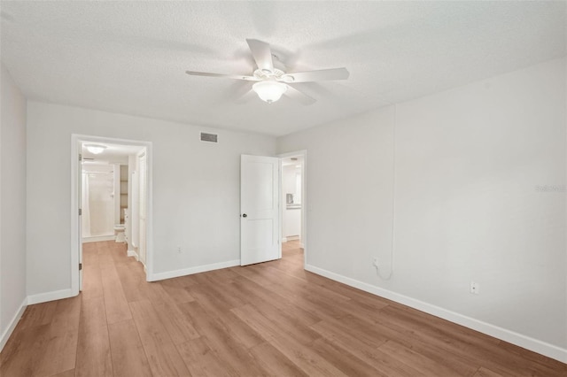 2753 Orchid Oaks Dr Unit 104, Sarasota, FL 34239 - unfurnished bedroom with light wood-style flooring, baseboards, a textured ceiling, connected bathroom, and ceiling fan