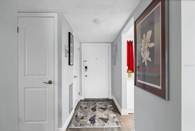 entryway featuring a textured ceiling and light hardwood / wood-style flooring