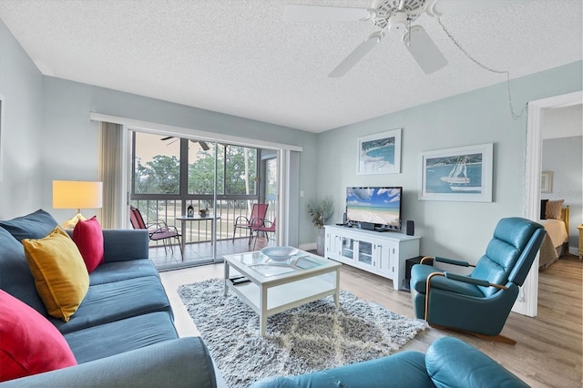 living room with ceiling fan, a textured ceiling, and light wood-type flooring