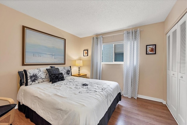 bedroom with wood-type flooring, a textured ceiling, and a closet