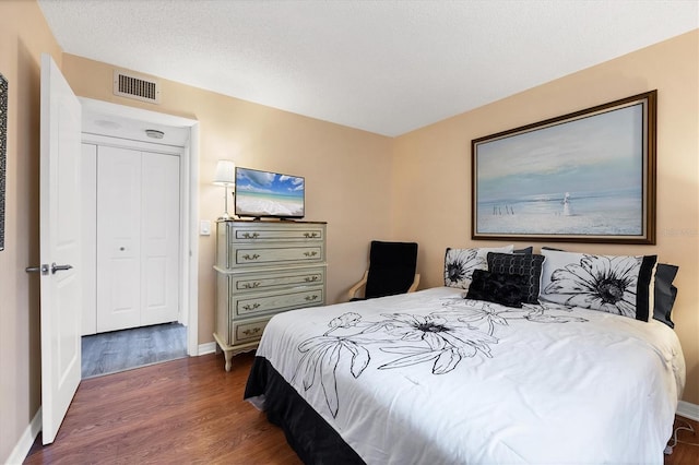 bedroom with dark hardwood / wood-style flooring and a closet