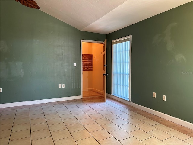 empty room with lofted ceiling and light tile patterned flooring